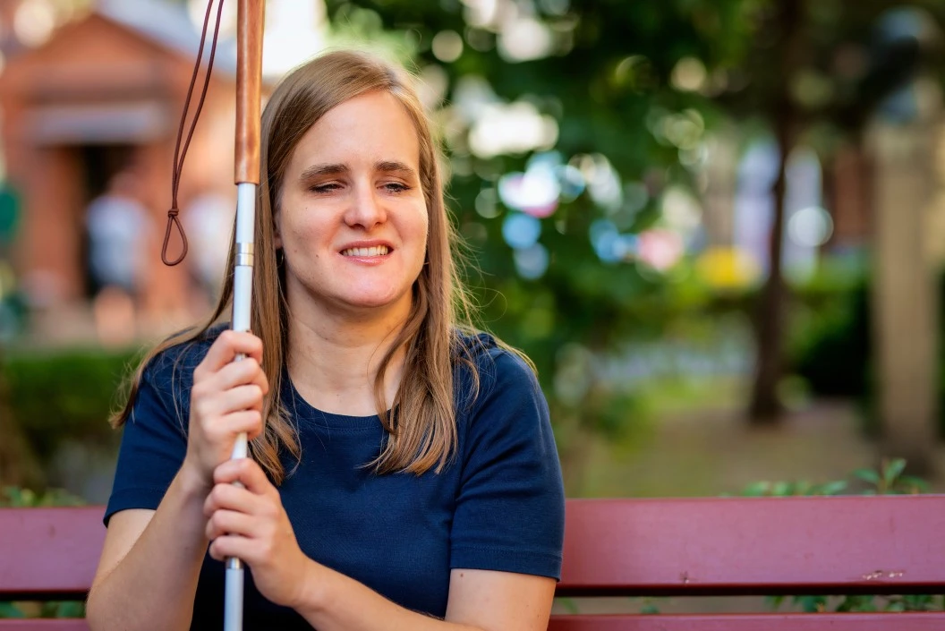 Blind woman sitting happily outside on park bench