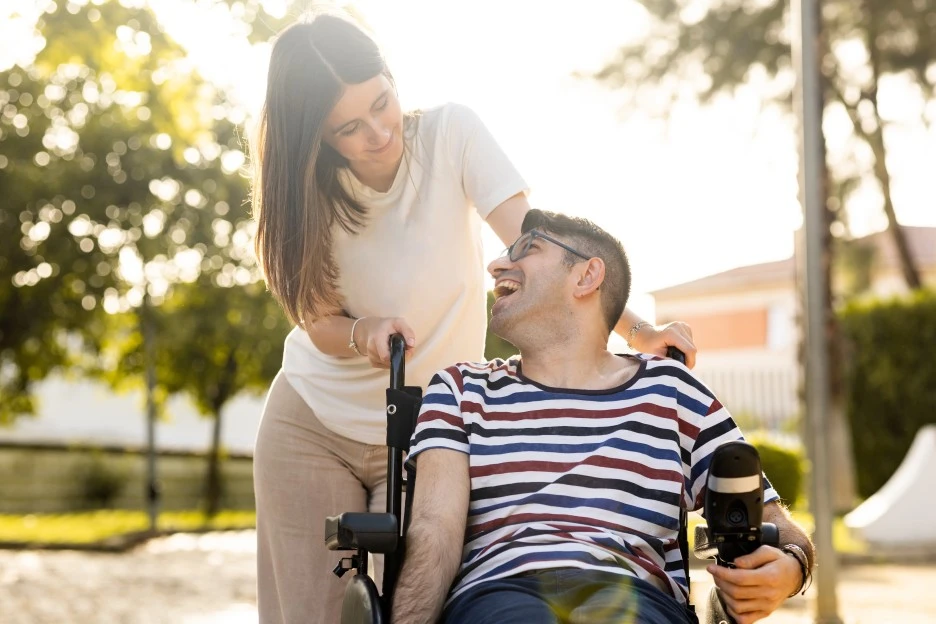Disabled man in wheelchair outside with support worker